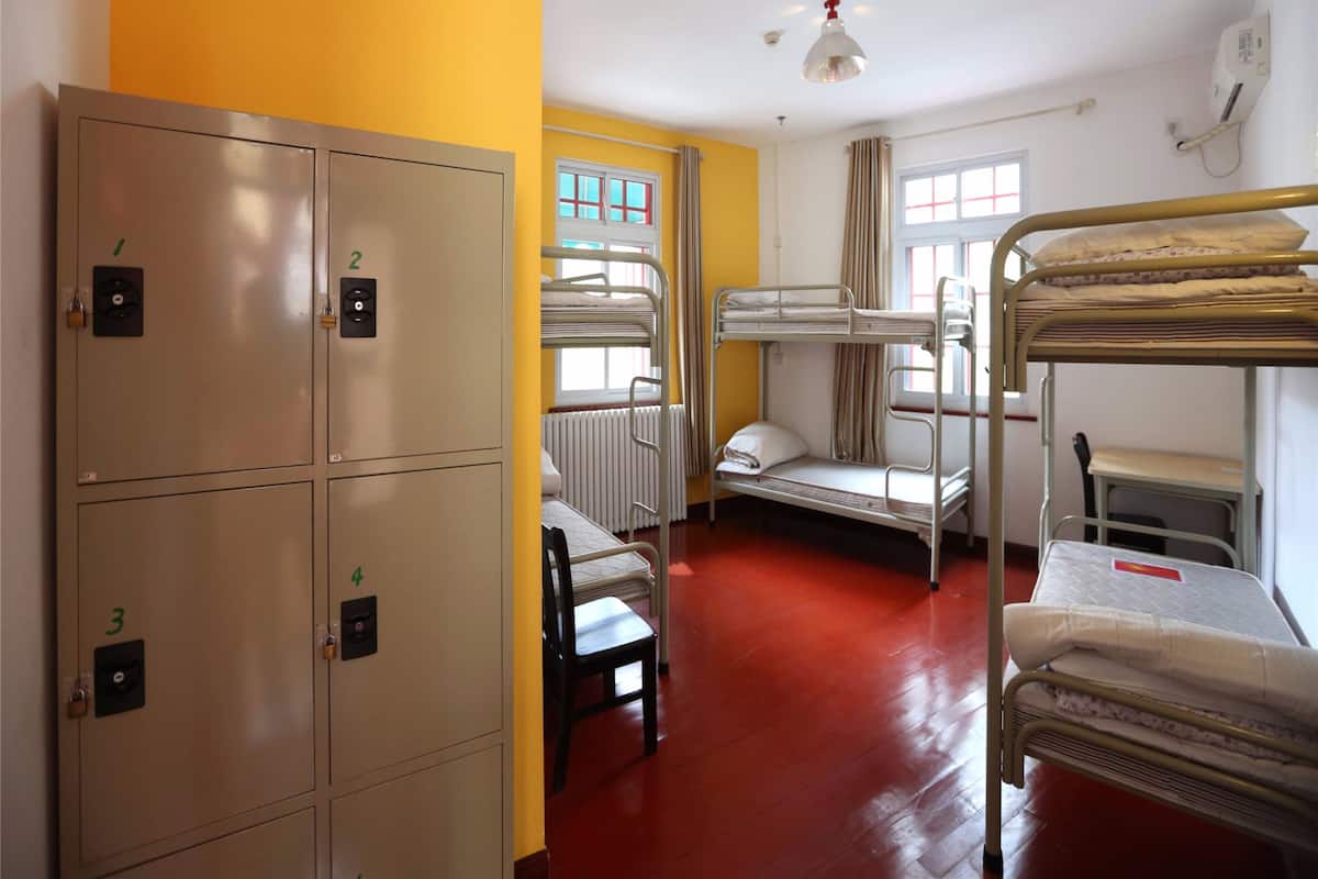 Une chambre de dortoir avec des lits superposés, une chaise et des casiers.