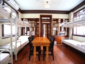 Un dormitorio con literas, una mesa de madera y sillas, y una puerta.