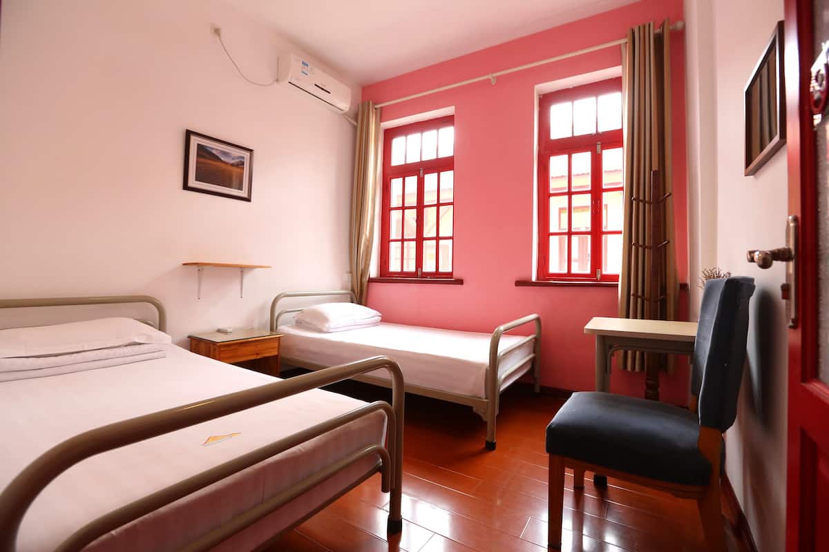 Une chambre d’hôpital avec deux lits, un bureau et une chaise.