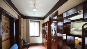 A hallway with a blue sofa, wooden cabinets, and a window with curtains. - Qingdao Wheat Youth Hostel (Qingdao)