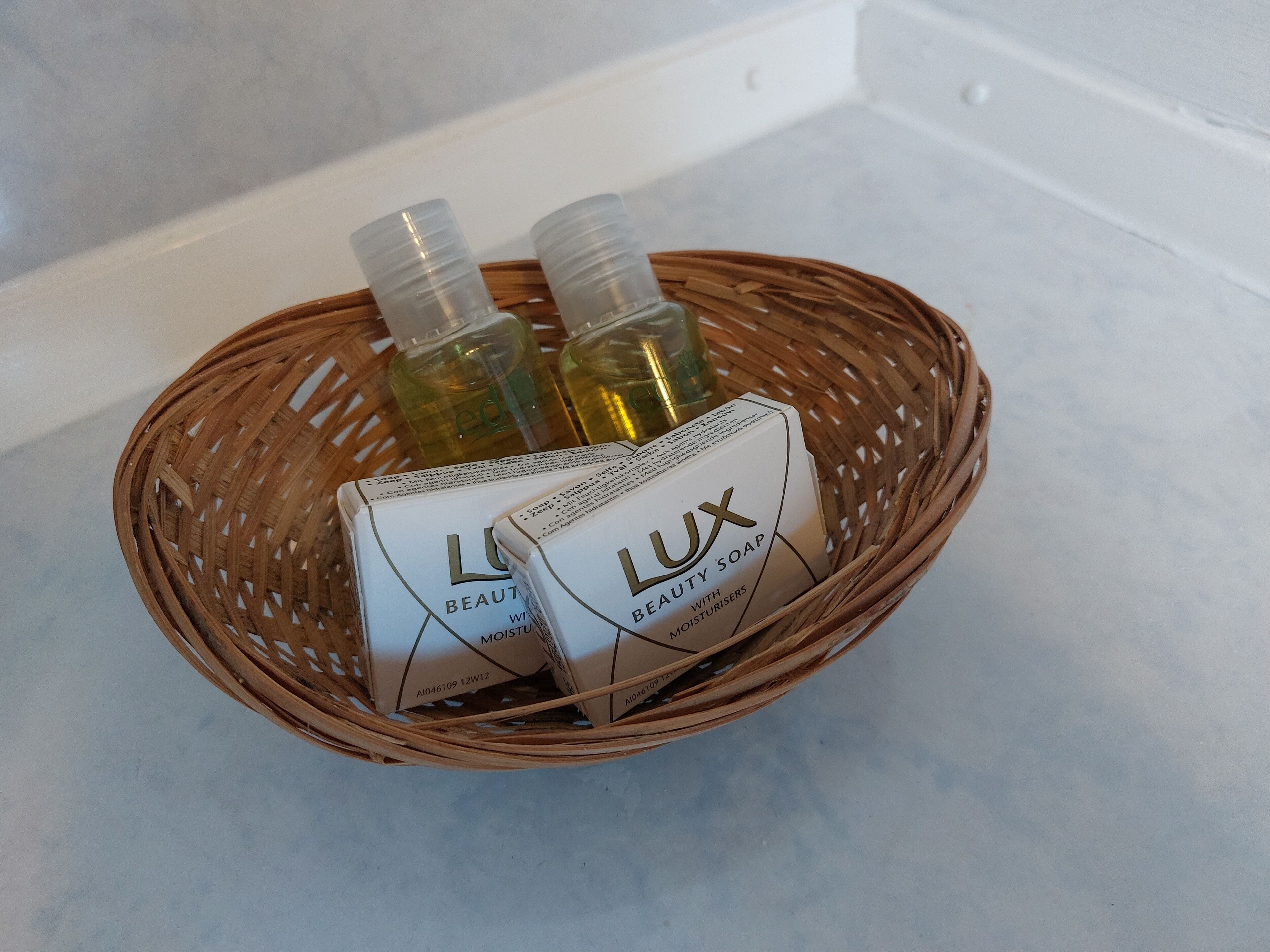 Un panier en osier contenant deux bouteilles de savon de beauté Lux et une boîte de savon de beauté Lux enrichi en agents hydratants.