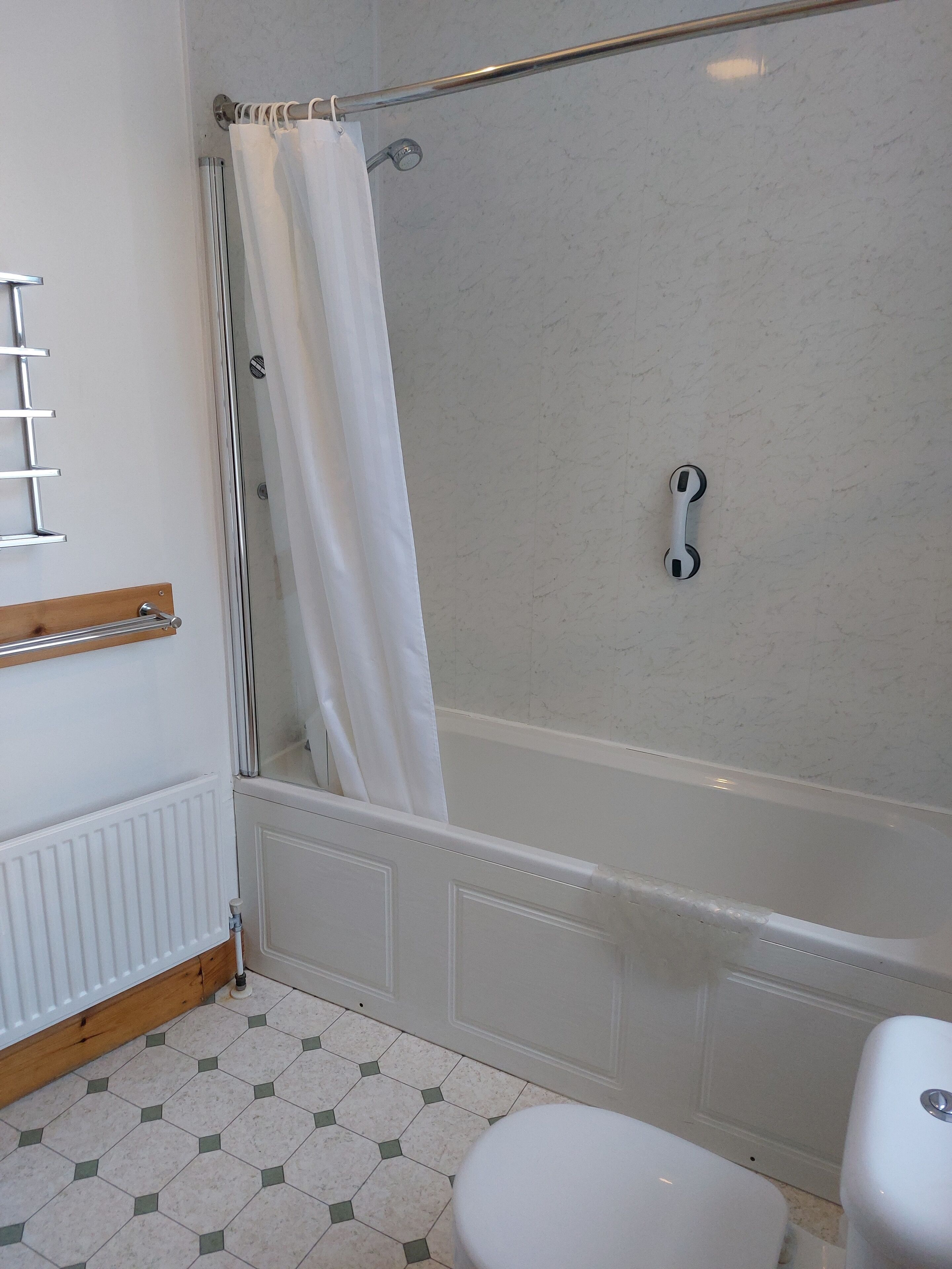 Un baño con ducha, inodoro y toallero.