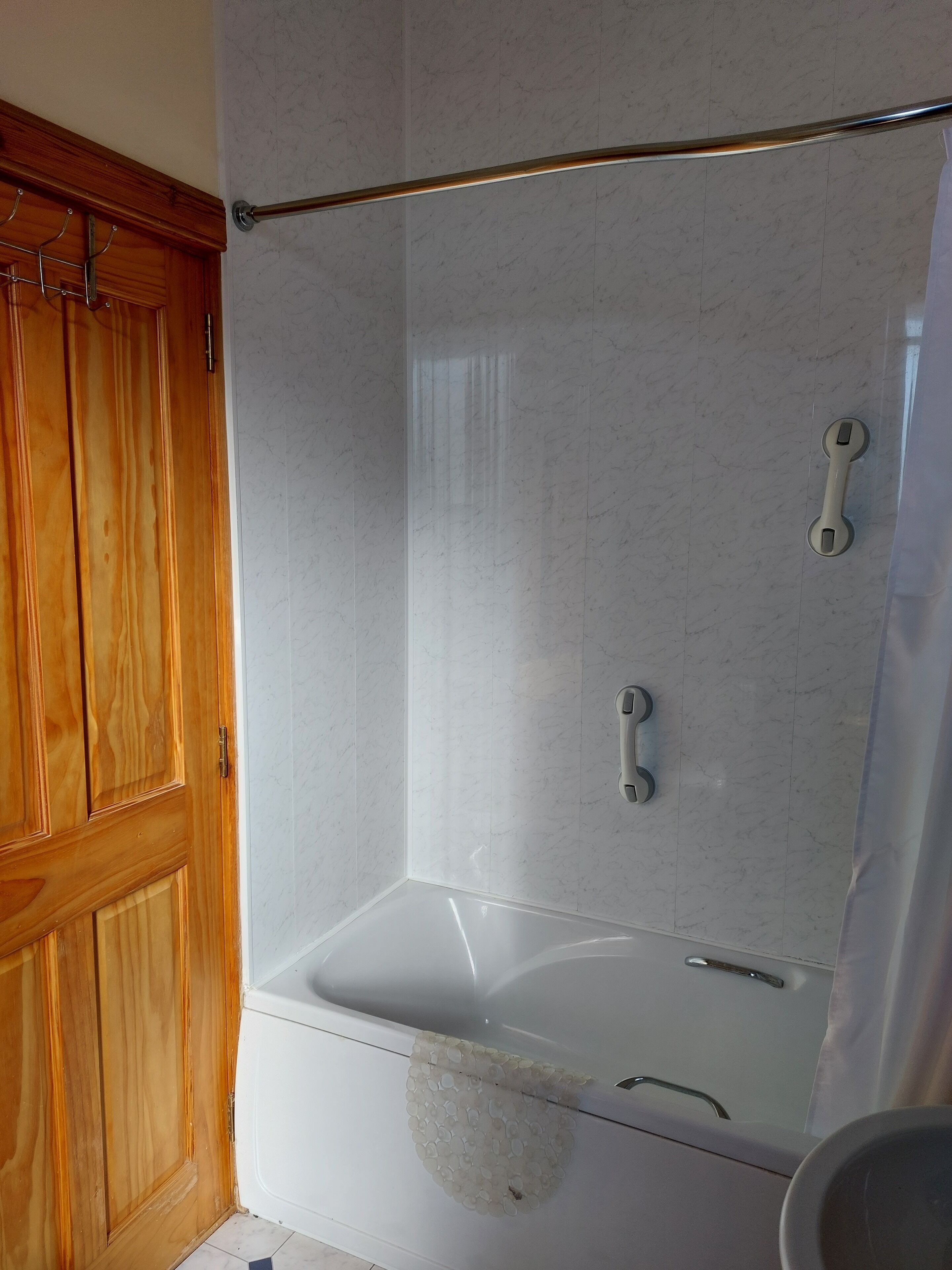 A bathroom with a wooden vanity, a white bathtub, and a shower area with a glass door.