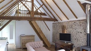 A cozy room with a wooden staircase, a stone fireplace, a television, and a comfortable sofa. - Shepherds Barn (Chichester)