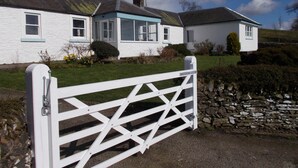 A white house with a blue roof and a stone wall. - Bluebell Bank (Dumfries)