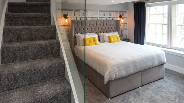 Un dormitorio con una cama grande, una escalera cubierta con cristal y vistas a un balcón.