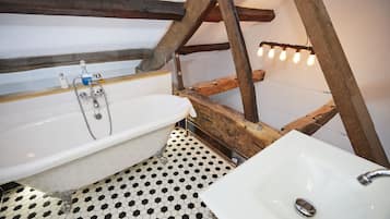 A bathroom with a white bathtub, a white sink, and a black and white tiled floor.