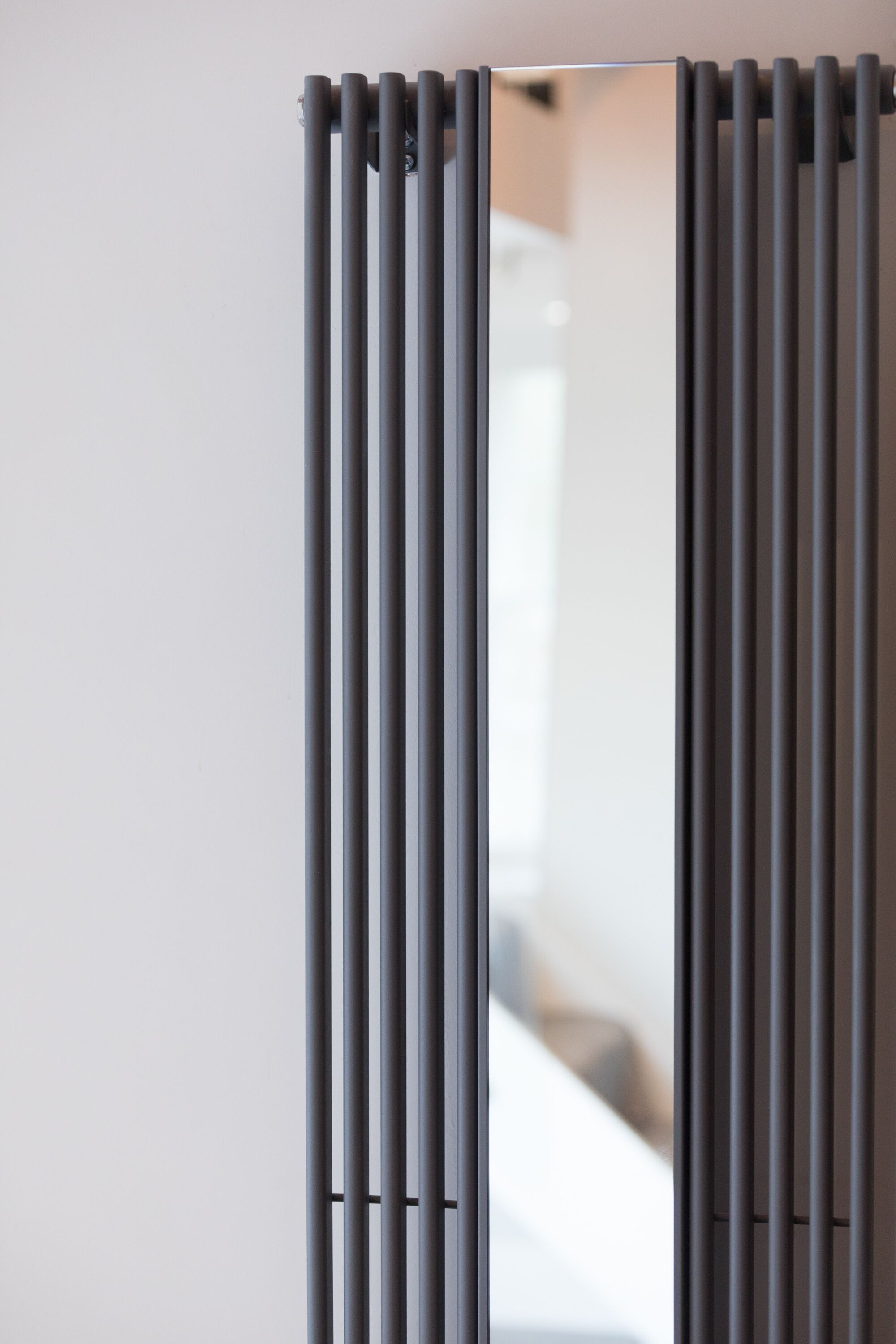 A modern, minimalist room with a grey, vertical radiator.
