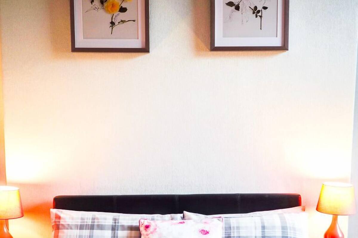A neatly made bed with a plaid bedspread and two pillows, flanked by nightstands with lamps.
