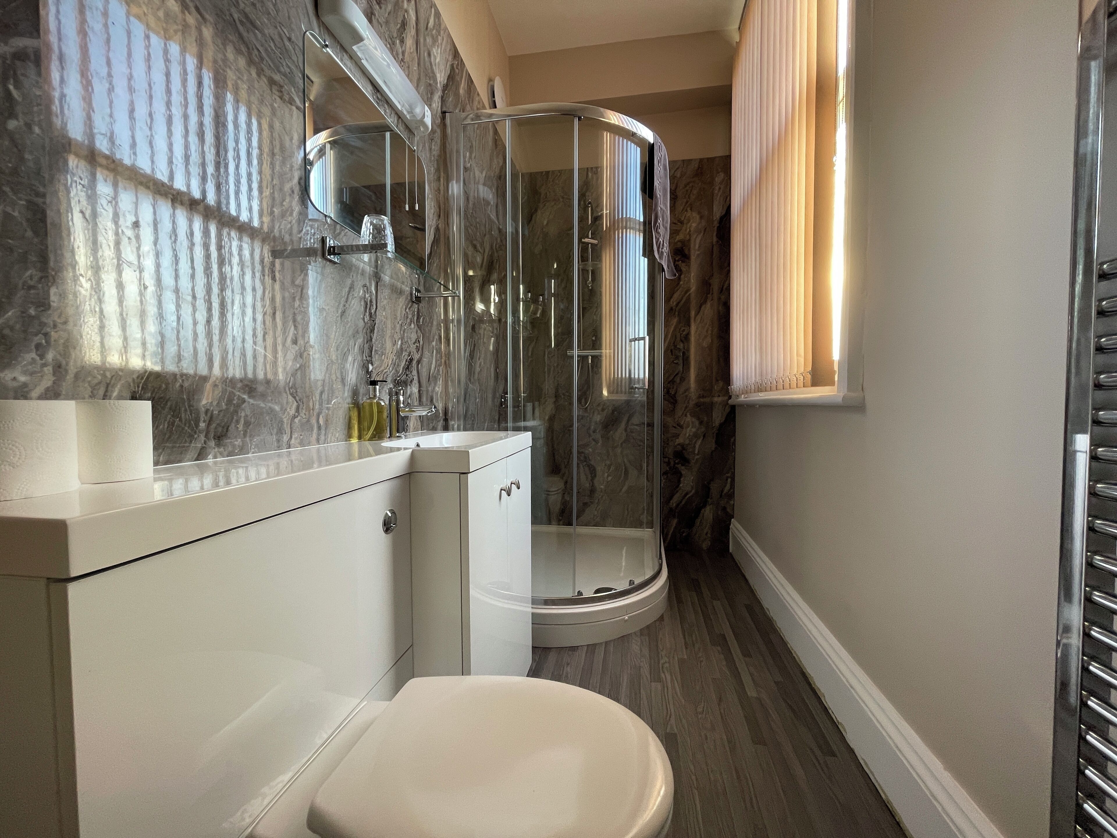 Une salle de bain moderne avec une douche à parois de verre, un meuble-lavabo blanc et des toilettes.