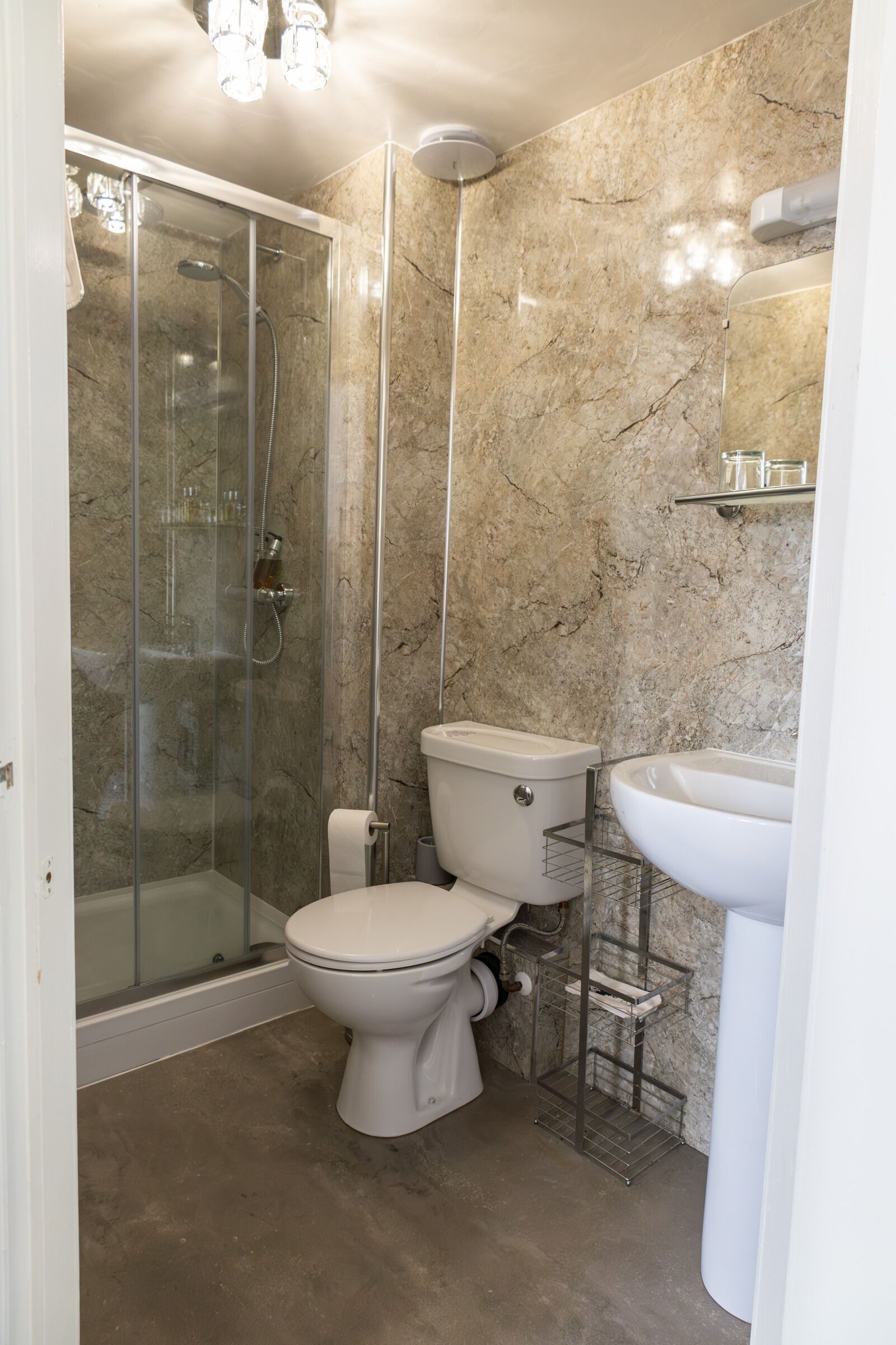 A bathroom with a glass-enclosed shower, a toilet, and a sink.