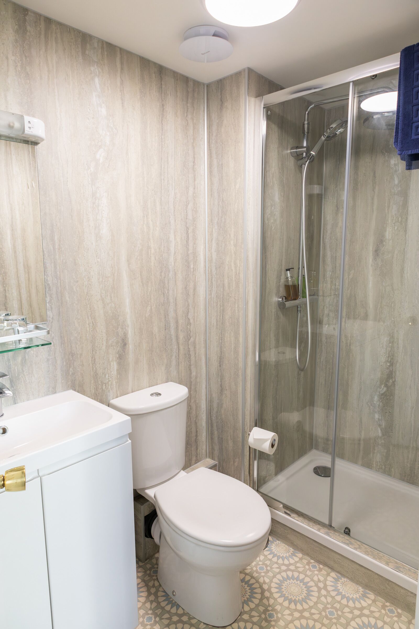 A bathroom with a glass-enclosed shower, a toilet, and a sink.