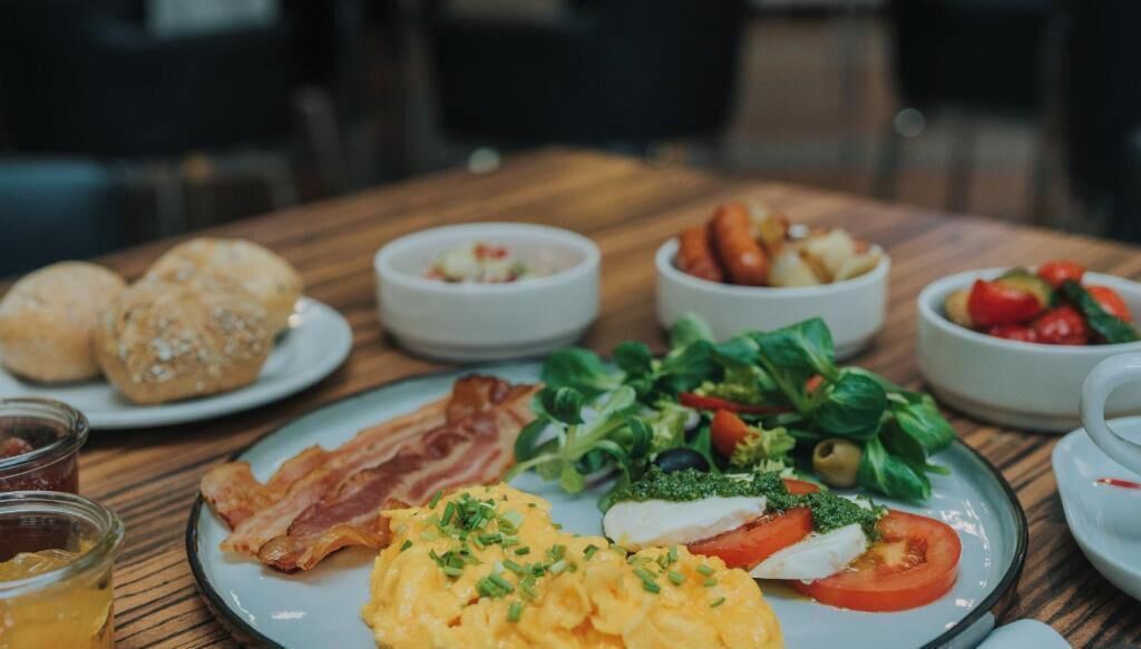 A breakfast setting with various dishes including eggs, bacon, and vegetables.