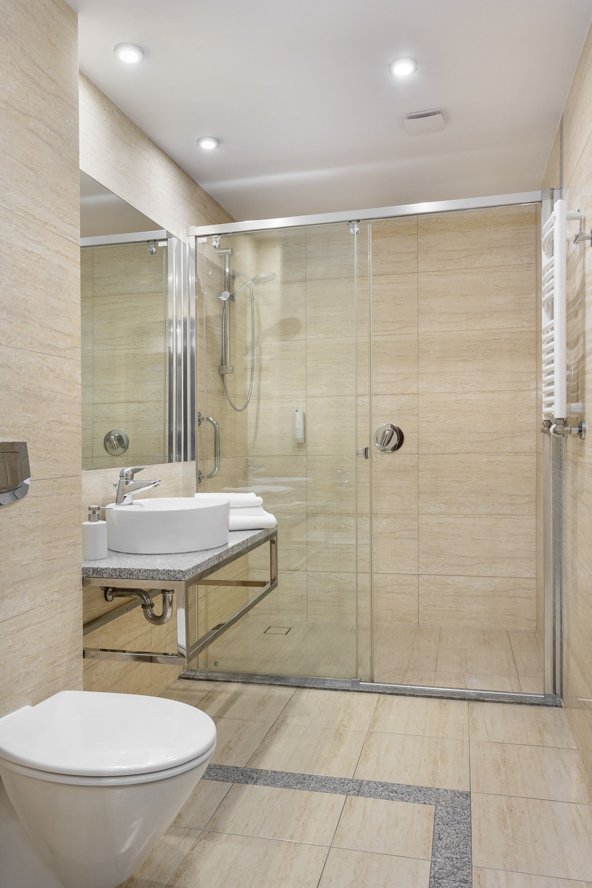 Een moderne badkamer met een douchecabine van glas, een wit wastafelmeubel en een toilet.