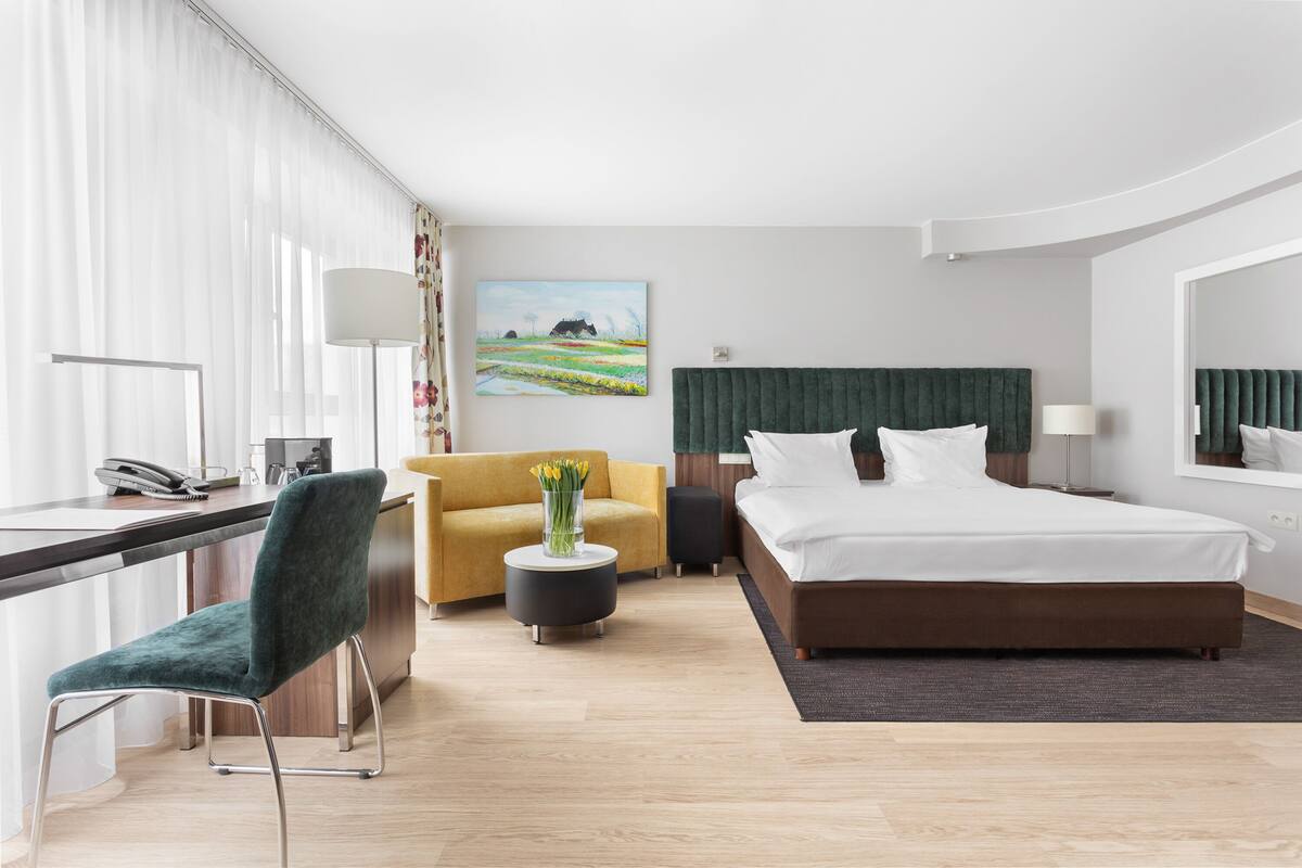Una camera d'albergo moderna con un letto, una scrivania, una sedia e un quadro appeso al muro.