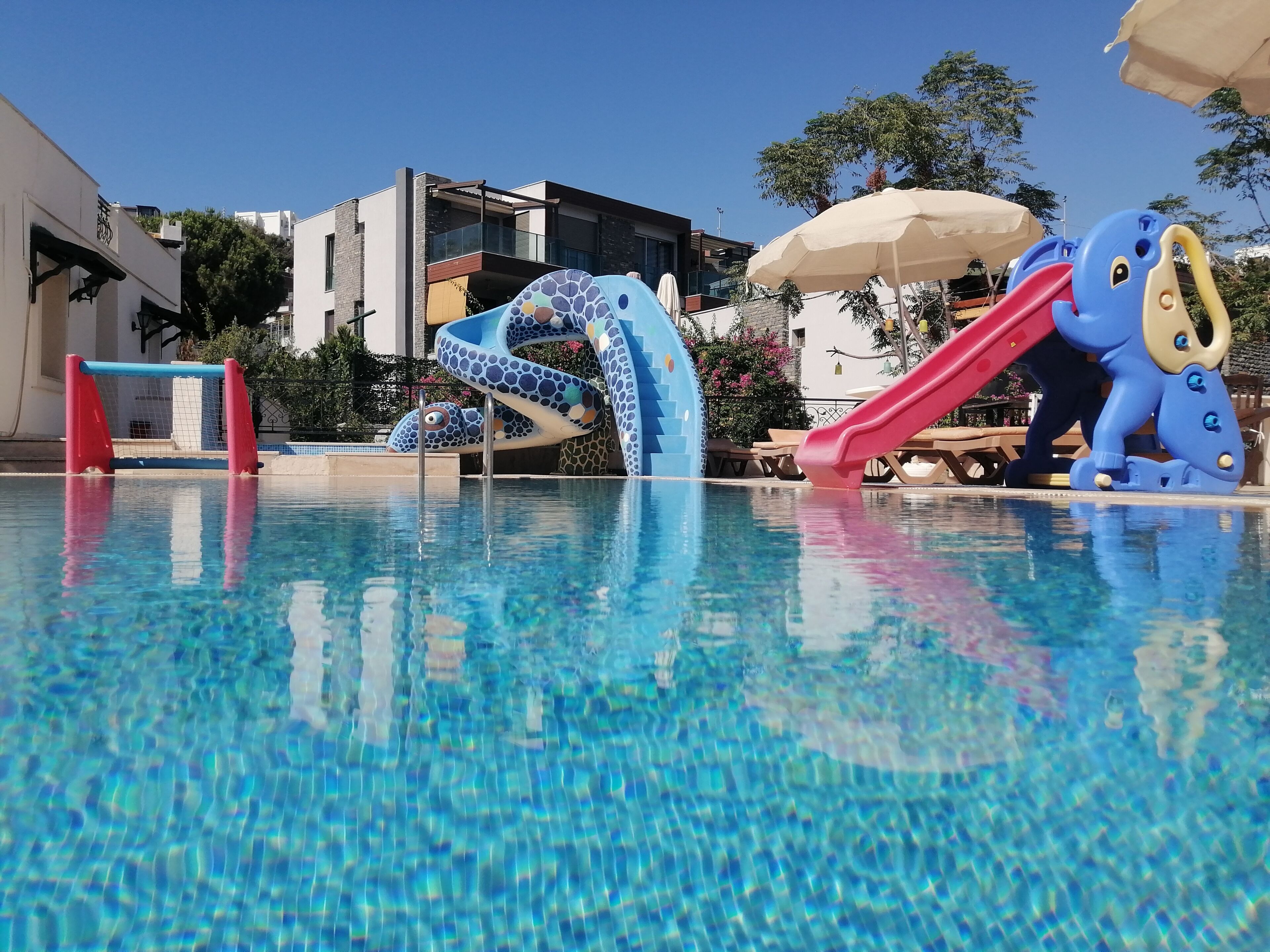 Una piscina con tobogán y estructura de escalada.