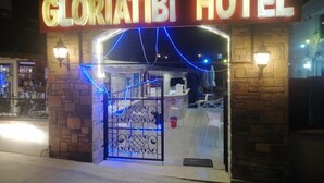 The exterior of the Gloriatibi Hotel with a stone facade, a metal gate, and blue decorative lights. - Gloria Tibi Hotel Gumbet (Bodrum)