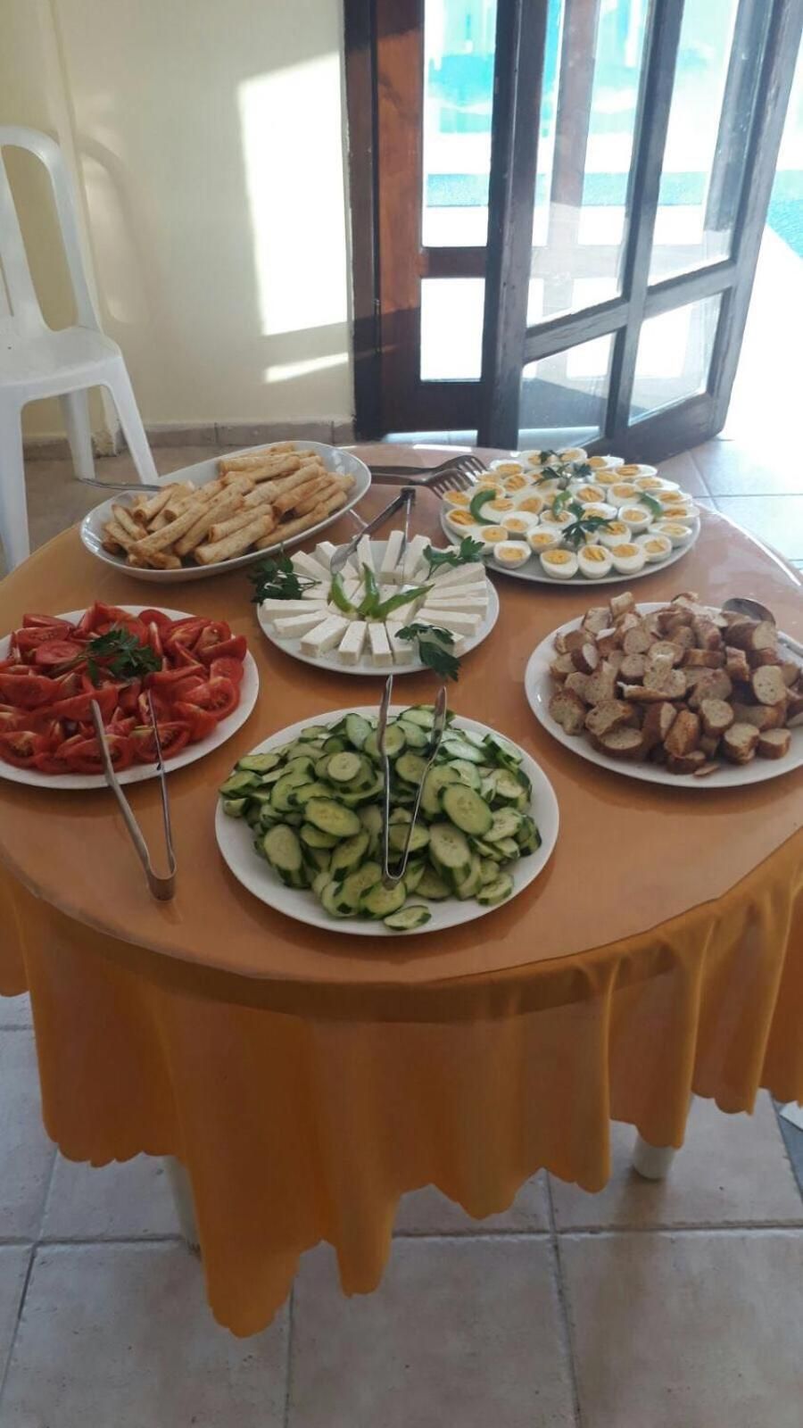 A table with various food items, including sliced cucumbers, tomatoes, cheese, and eggs.