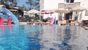 A swimming pool with clear blue water, surrounded by lounge chairs and umbrellas. - Gloria Tibi Hotel Gumbet (Bodrum)