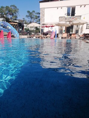 Una piscina al aire libre de temporada, sombrillas, tumbonas