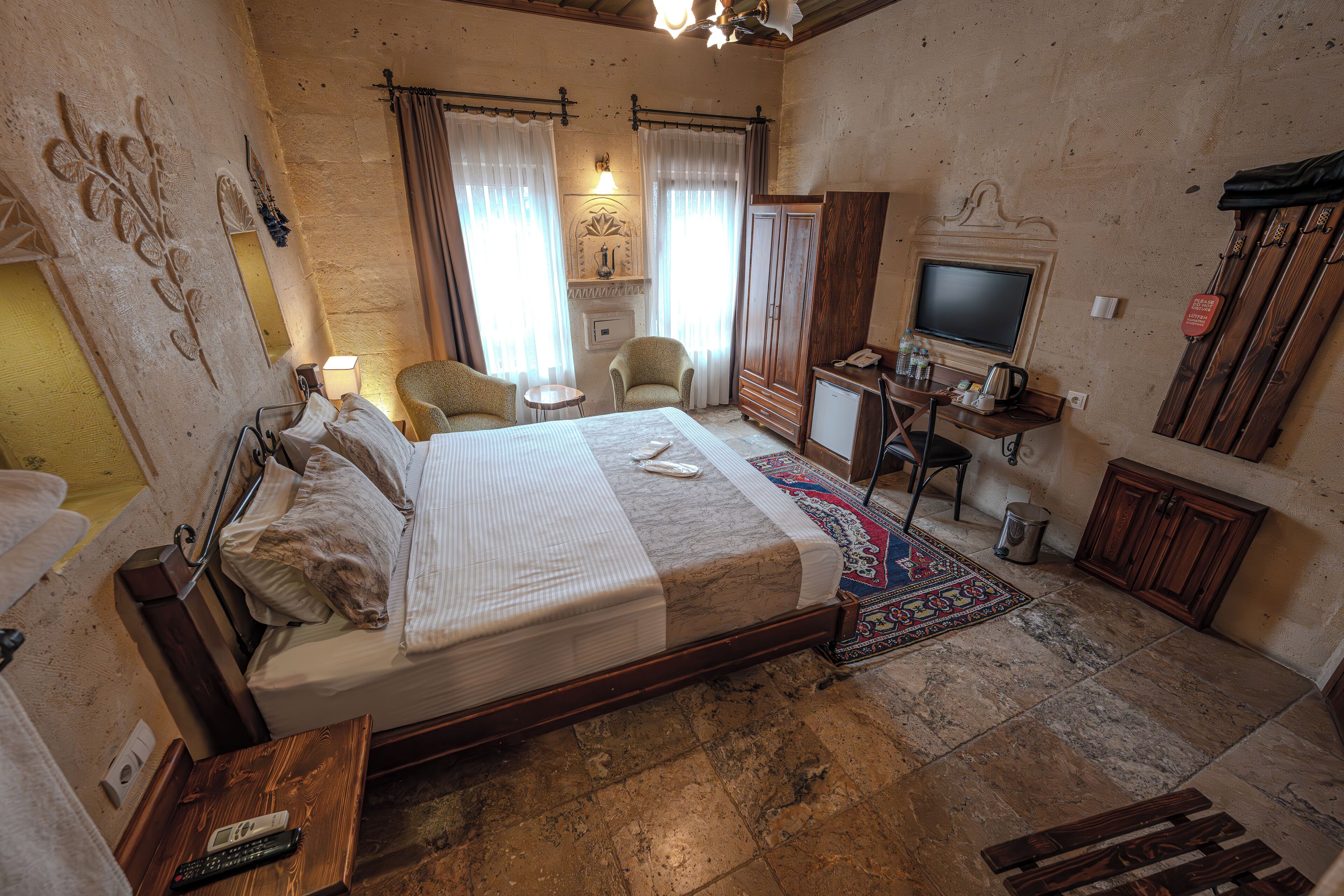 Ein Schlafzimmer mit einem Bett, zwei Sesseln, einem Schreibtisch mit Fernseher, einem Kamin und einem Kleiderschrank.