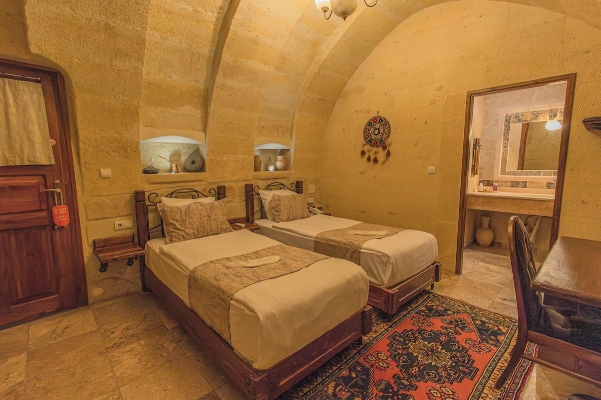 A room with two beds, a wooden door, a mirror, and a patterned rug.