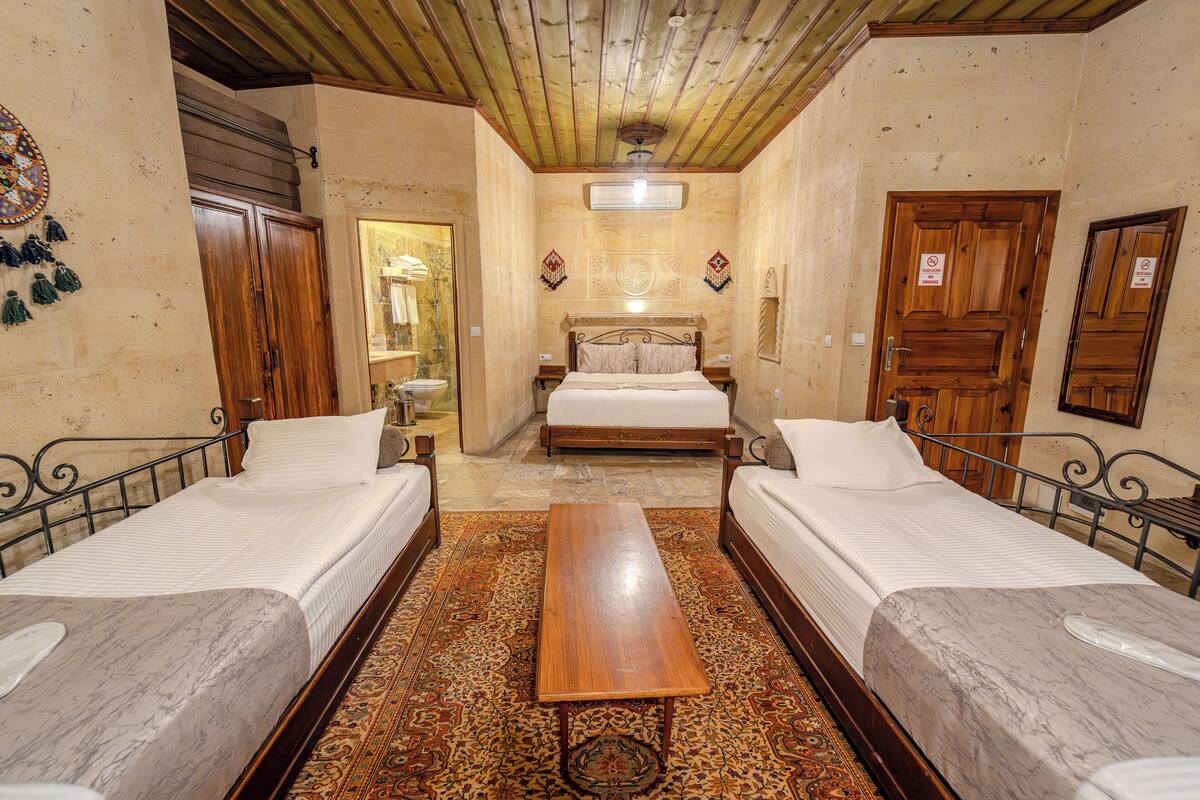 A room with two single beds, a wooden table, and a patterned rug.