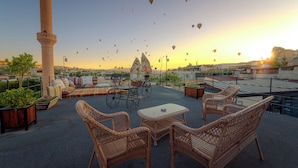 Terraza en la azotea con mobiliario de mimbre, una bicicleta y vistas del paisaje urbano y un alminar.