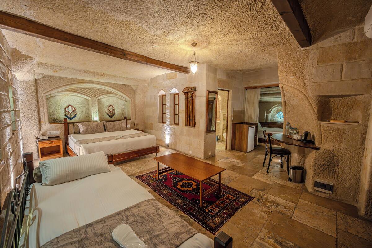 A cozy room with a bed, a wooden table, and a small kitchen area.