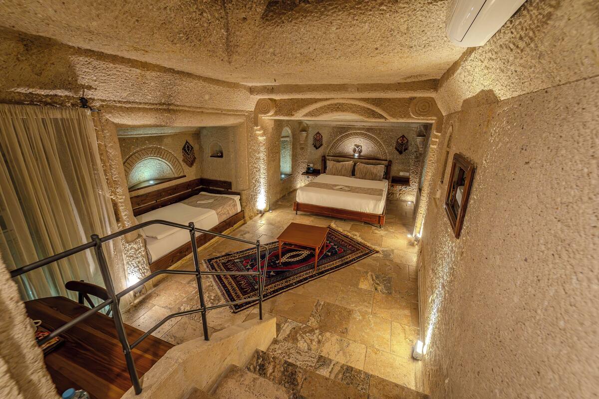 A room with a bed, a small table, a chair, and a staircase.