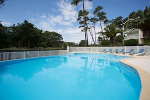 A swimming pool with lounge chairs and a white fence. - Madame Vacances Les Palmiers du Golf (Moliets-et-Maa)