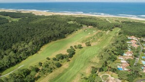 An aerial view of a coastal area with a golf course, dense forest, and a beach. - Madame Vacances Les Palmiers du Golf (Moliets-et-Maa)