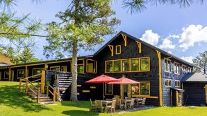 A log cabin with a porch, outdoor seating, and a staircase leading to the entrance. - Adirondack Spruce Lodge (Wilmington)