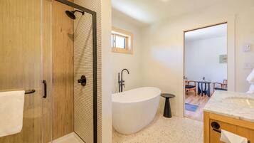 A modern bathroom with a glass-enclosed shower, a freestanding bathtub, and a wooden vanity.