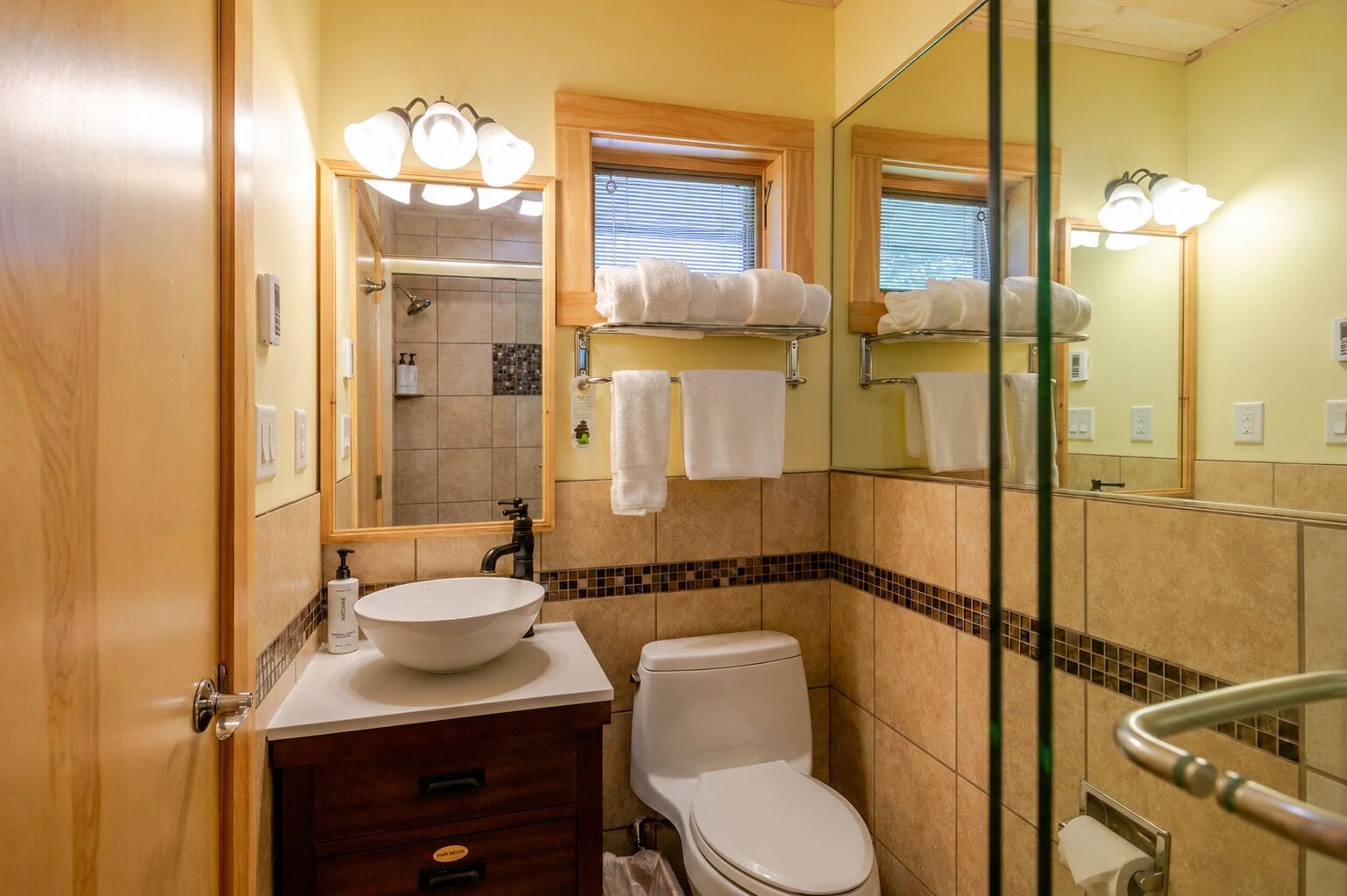 A bathroom with a sink, toilet, and shower. There are towels hanging on a rack and a mirror above the sink.