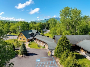 A lodge with a large building and a smaller structure, surrounded by trees and a parking area. - Adirondack Spruce Lodge (Wilmington)