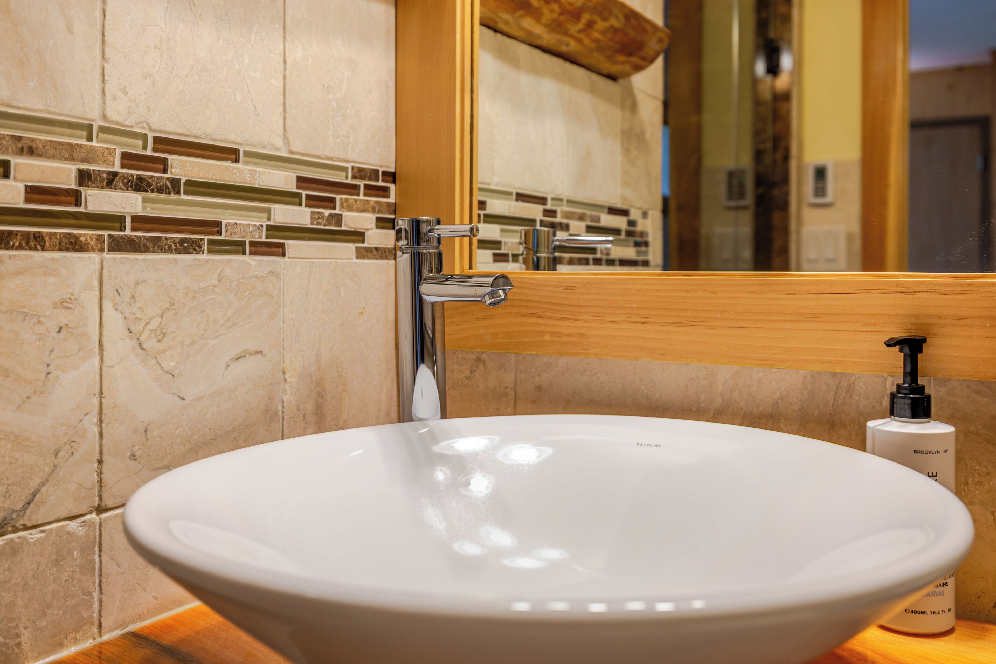 A bathroom with a white sink, chrome faucet, and a mirror above it.