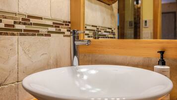 A bathroom with a white sink, chrome faucet, and a mirror above it.