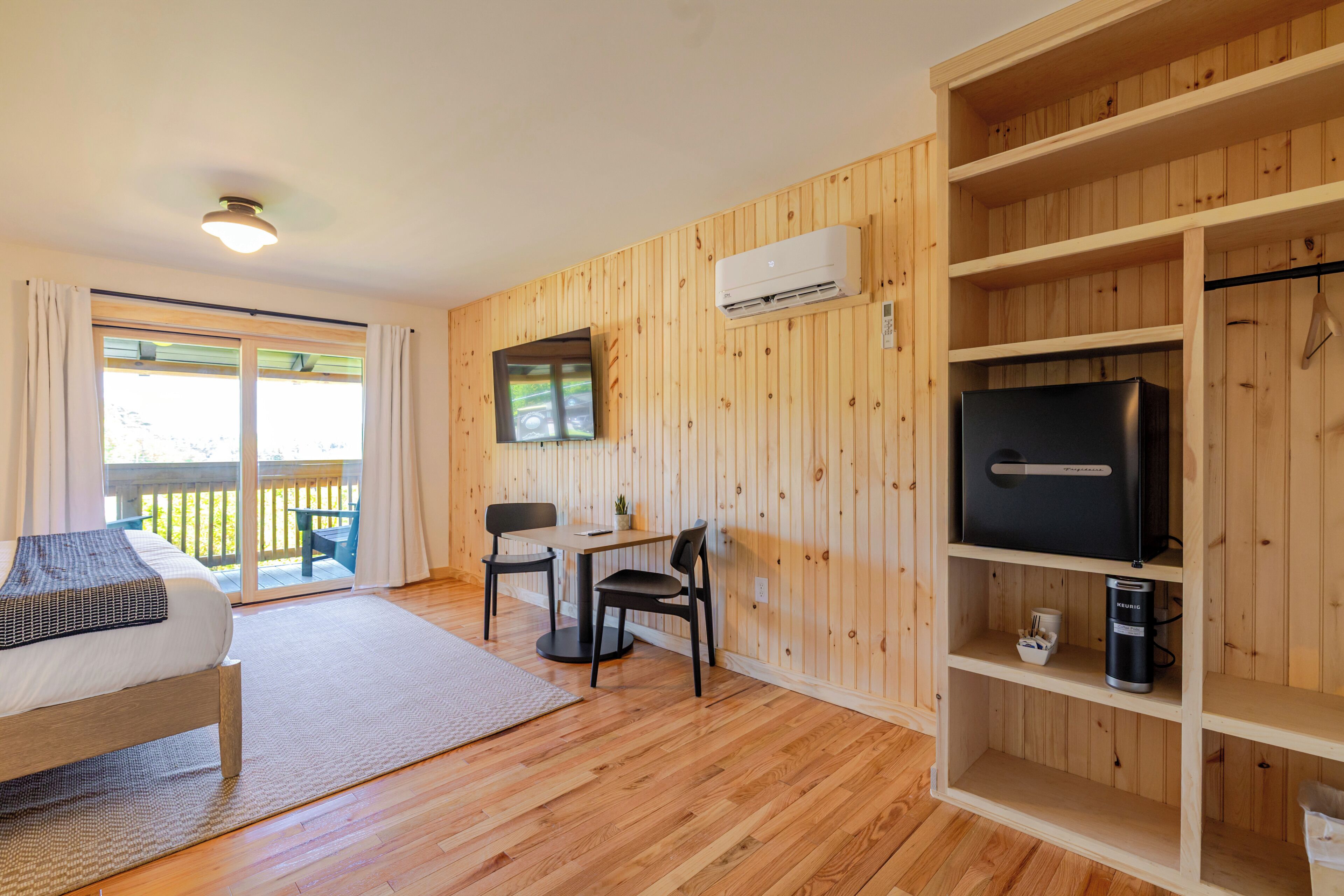 Une chambre comprenant un lit, un bureau avec des chaises, une télévision et un appareil de climatisation.