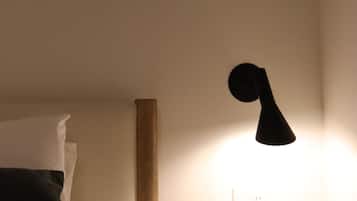 Ein Bett mit Kissen, ein Nachttisch und eine Wandlampe.