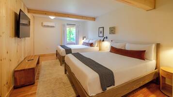 Un dormitorio con dos camas, televisión, aire acondicionado y una ventana con cortinas.