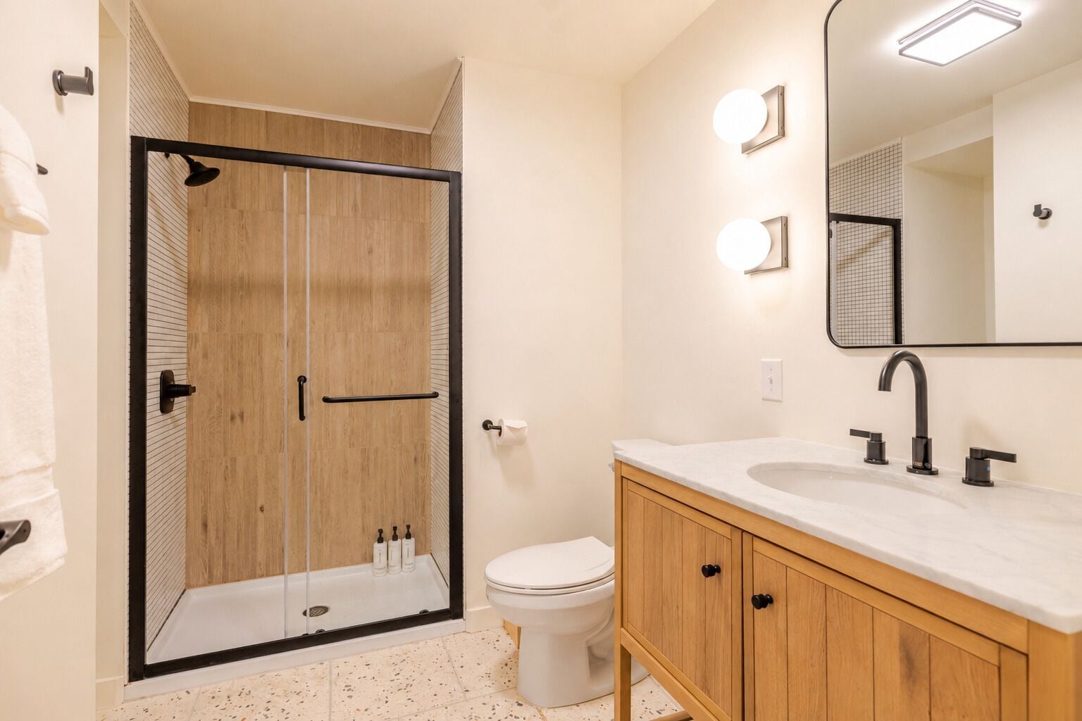Baño con ducha, inodoro, tocador y espejo.