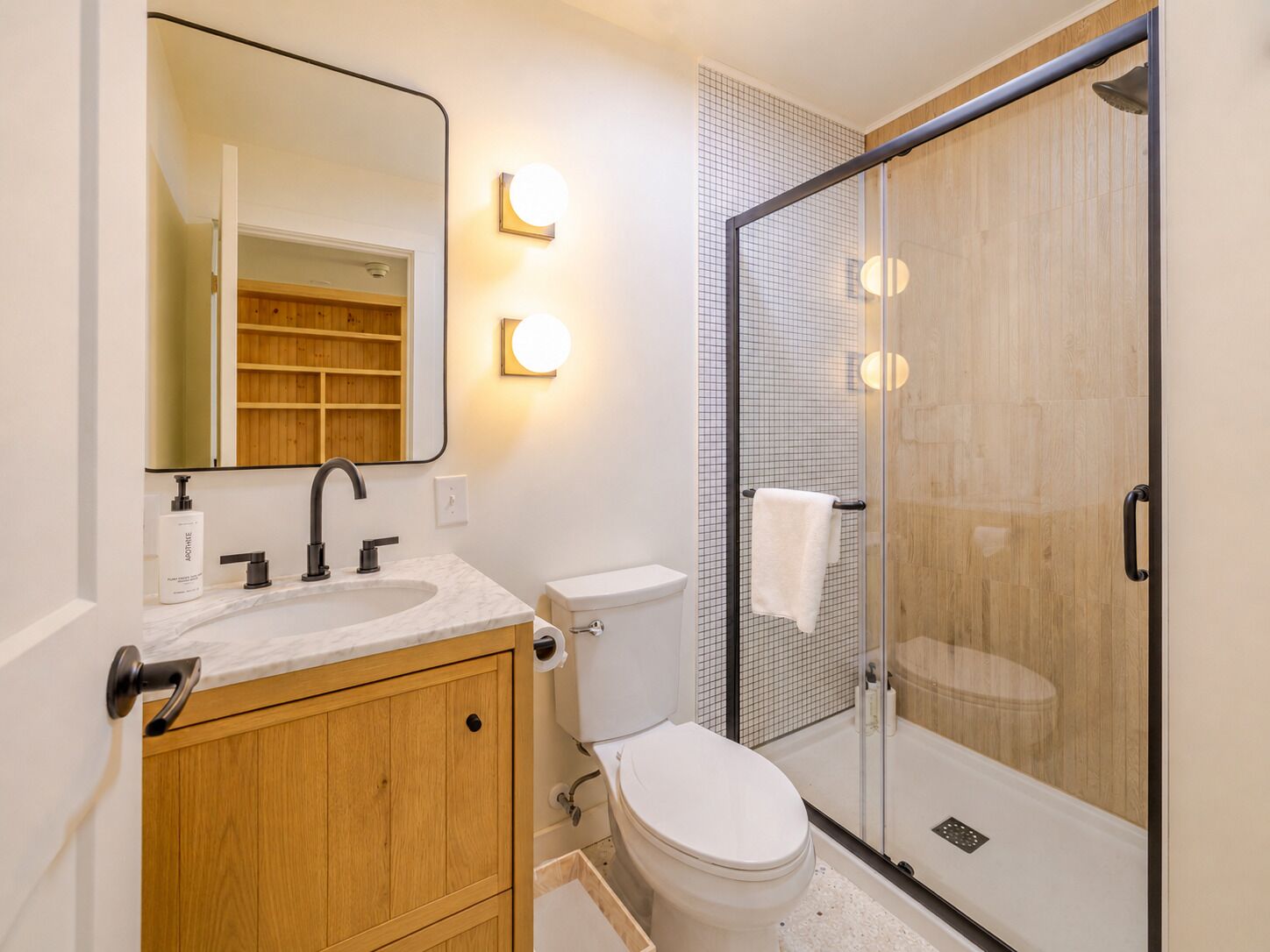 Ein modernes Badezimmer mit einem Holzwaschtisch, einer Duschkabine aus Glas und einer weißen Toilette.