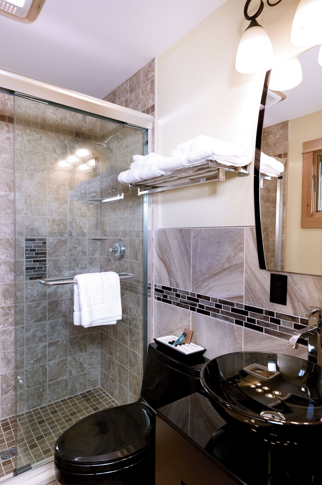 A modern bathroom with a glass-enclosed shower, a black vanity with a sink, and a mirror above the vanity.