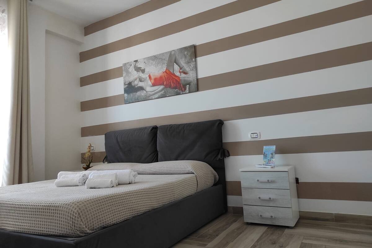 A modern bedroom with a bed, a nightstand, and a painting on the wall.