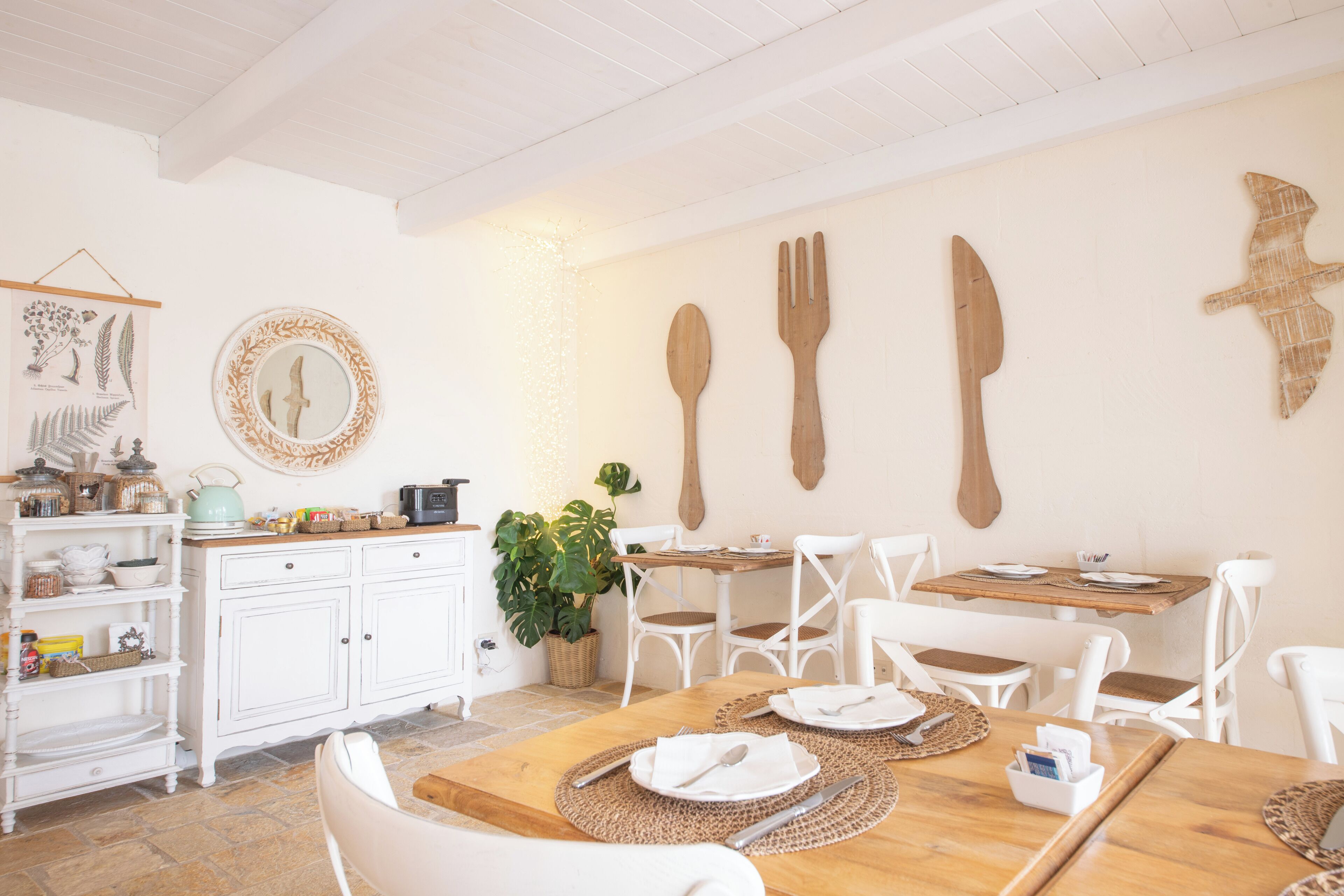A dining area with white chairs, a wooden table, and a buffet with white cabinets.