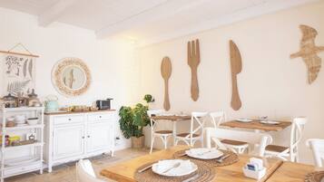 Un coin repas avec des chaises blanches, une table en bois et un buffet doté de meubles blancs.