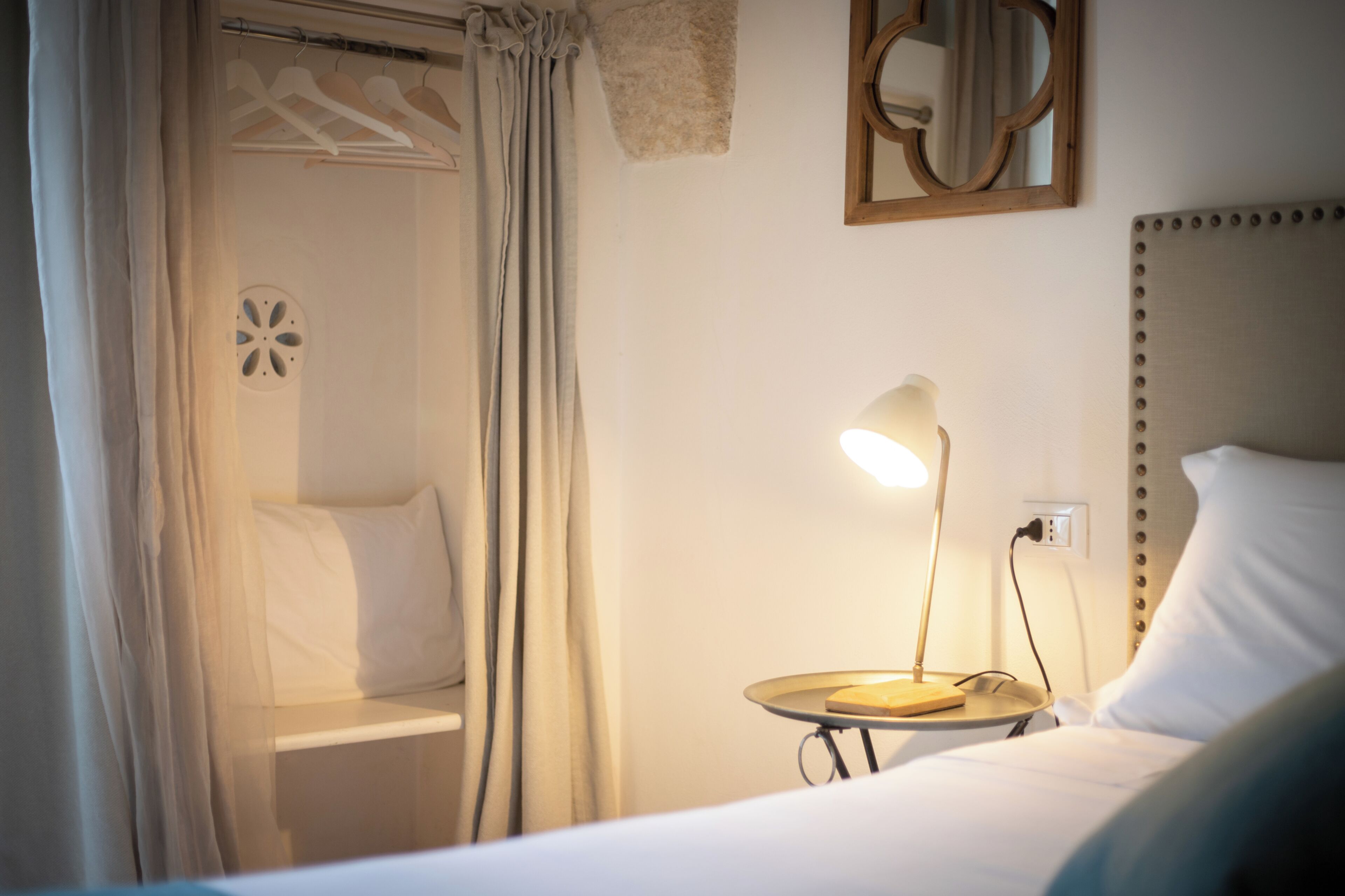 Ein Hotelzimmer mit Bett, Nachttisch, Lampe und einer Kleiderstange.