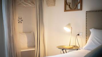 Ein Hotelzimmer mit Bett, Nachttisch, Lampe und einer Kleiderstange.