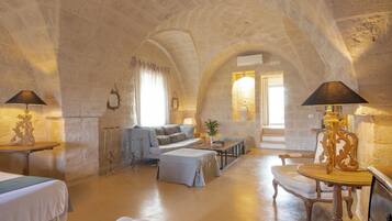 A spacious living room with a stone vaulted ceiling, a sofa, a coffee table, and a lamp.